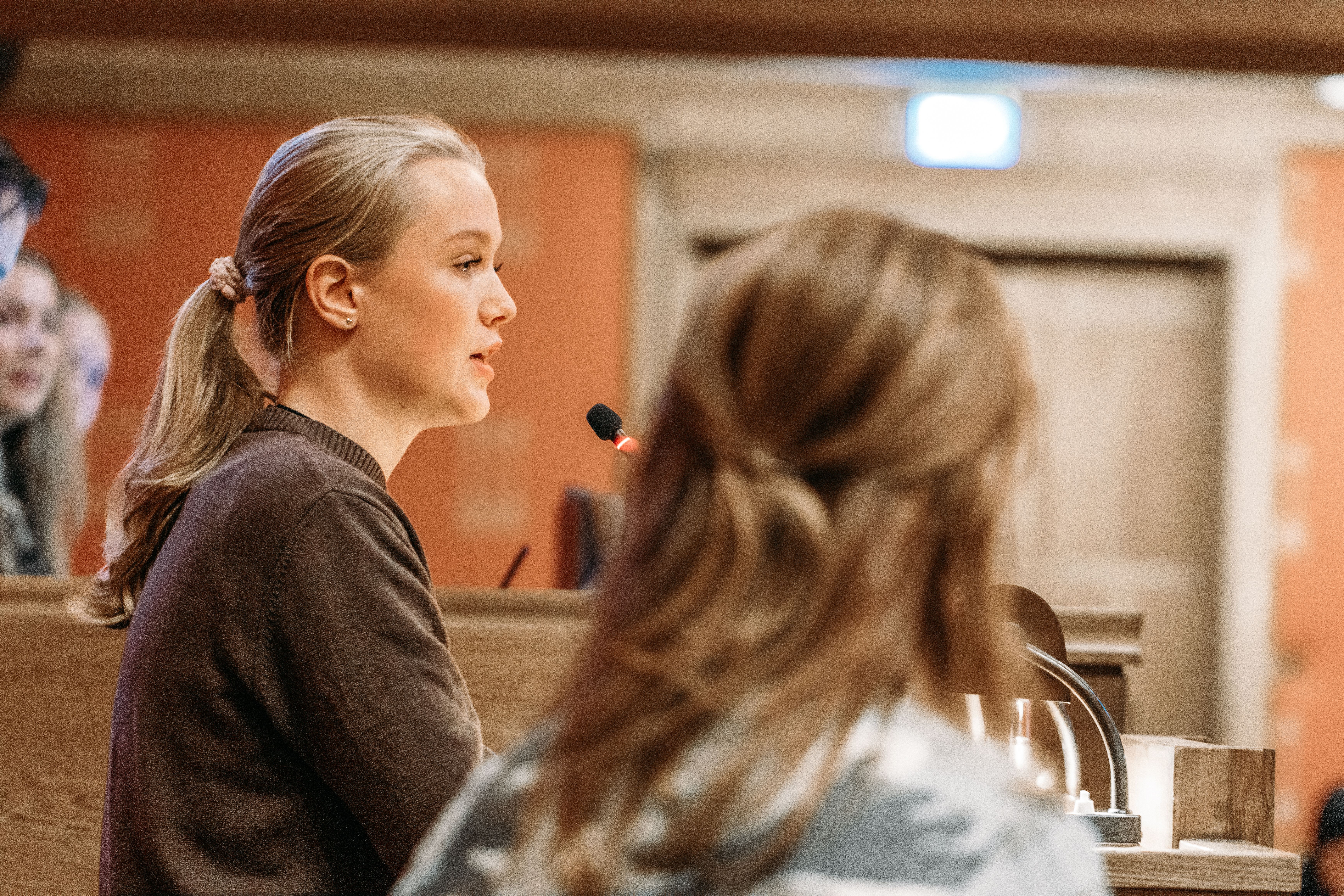 En av jentene står på talerstolen og snakker til de andre ungdommene i salen
