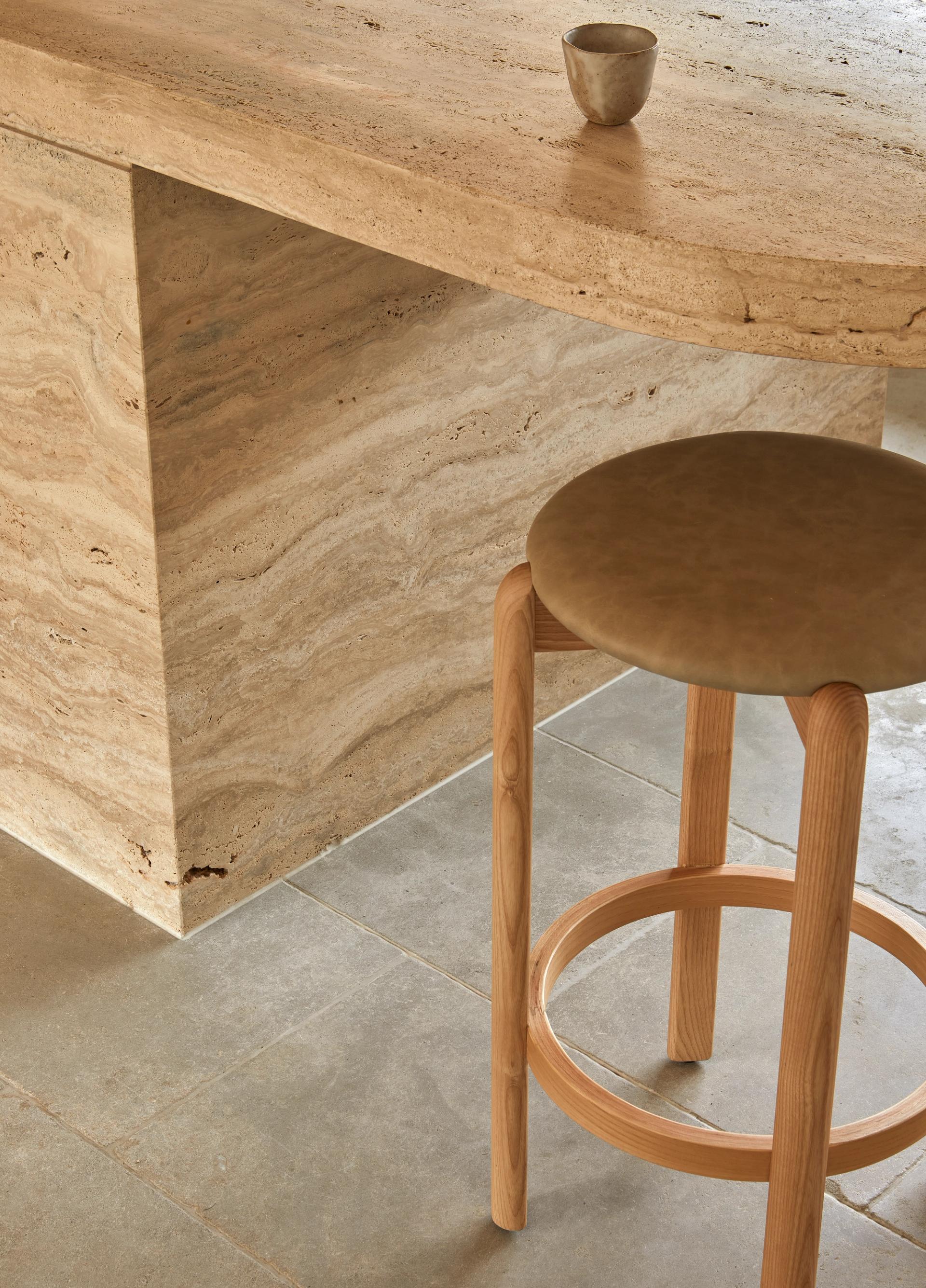 Travertine kitchen island detail at Barwon Dunes House, complemented by limestone flooring and timber bar stools.