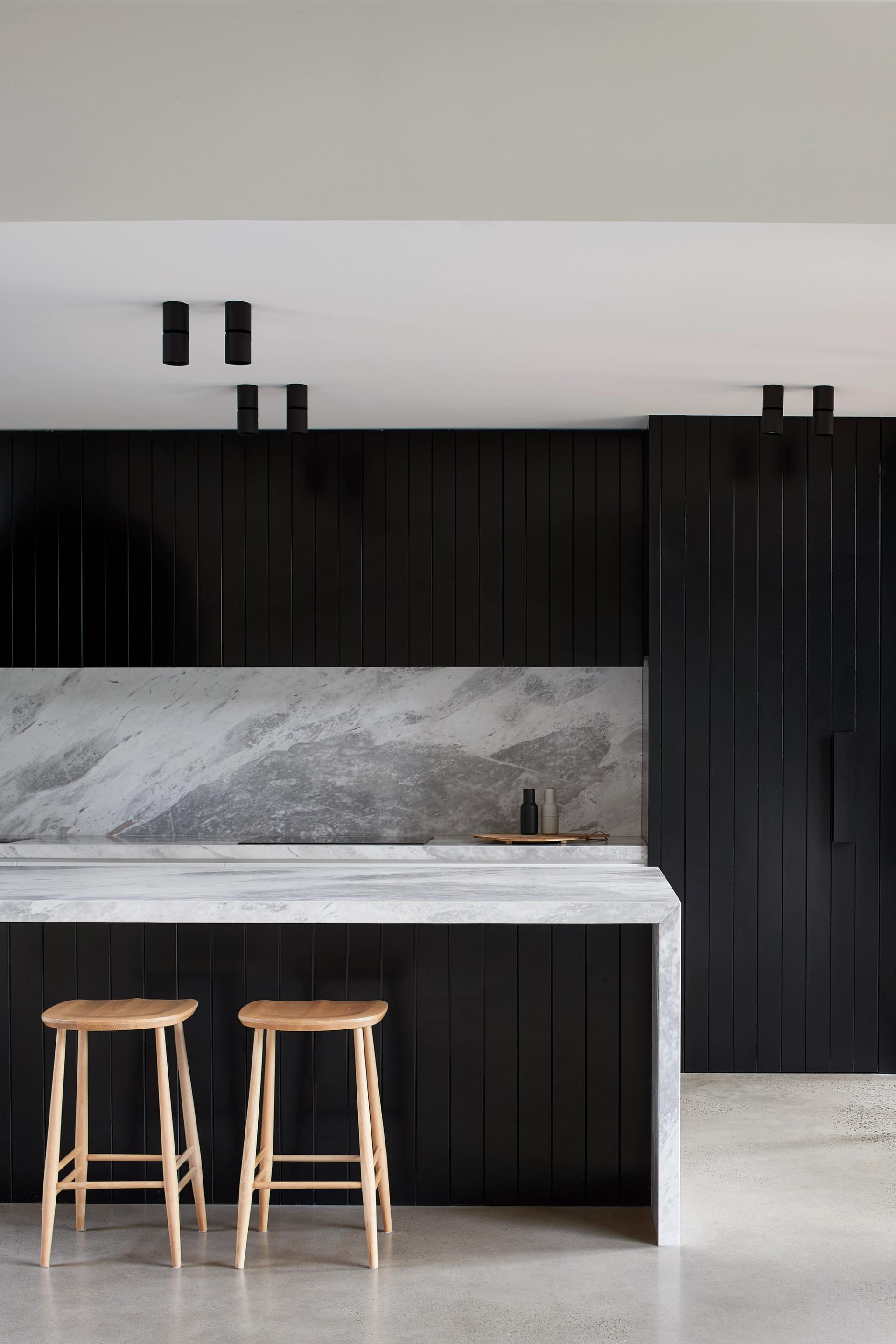 The kitchen's stone and black cabinetry connects to the external materials.