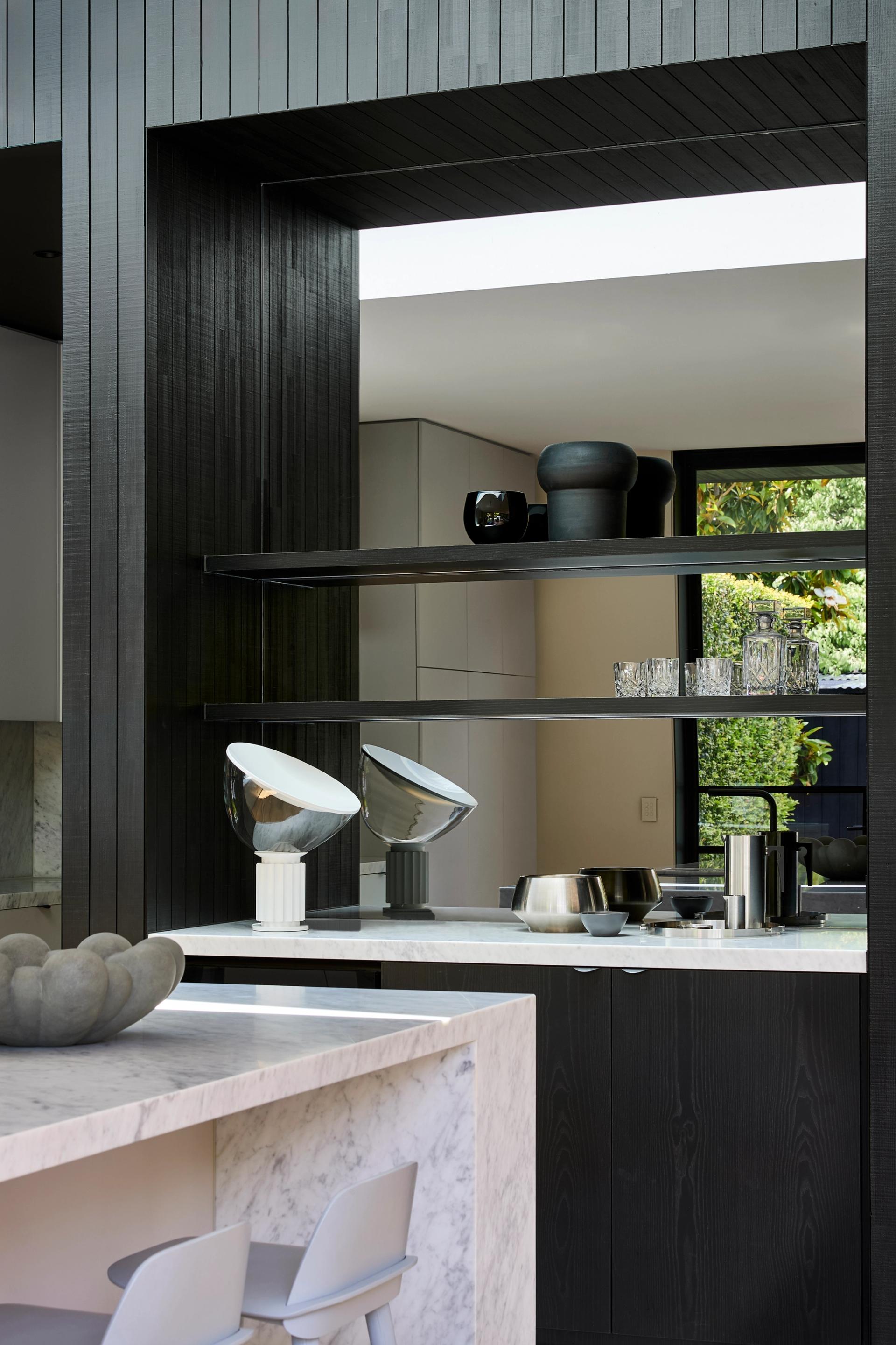 A refined palette of white walls, grey cabinetry, marble and terrazzo surfaces are accented with black elements.