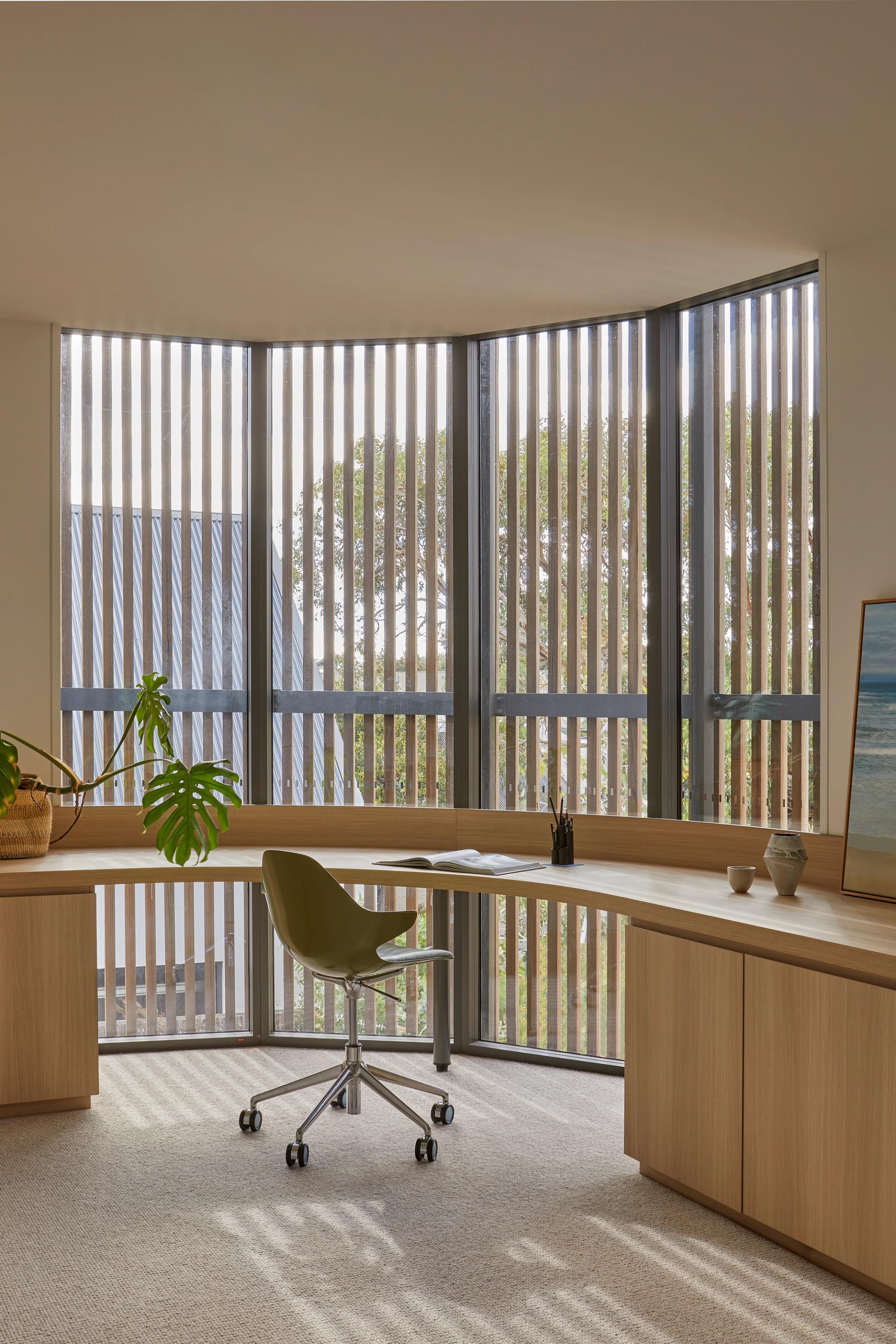 A curved study window wall provides a quiet place to work with filtered light through the screening
