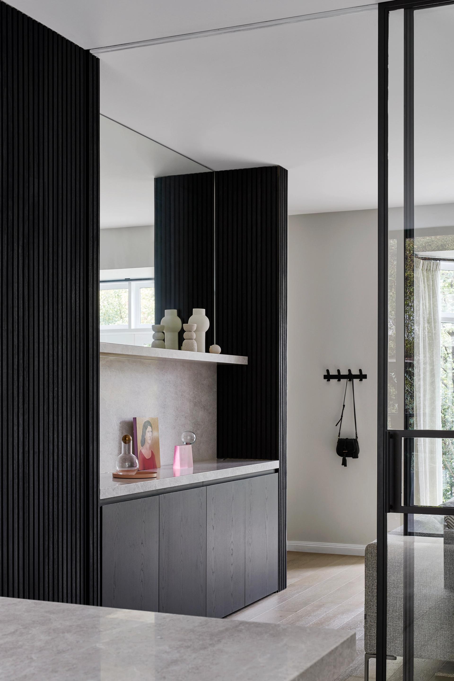 White and grey tones contrast with the black-coated steel window and door frames.