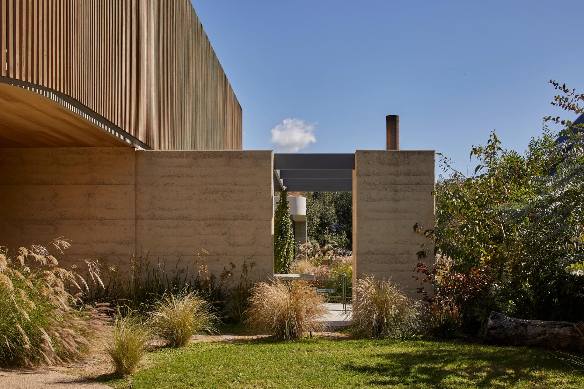 Barwon Dune House garden entry with rammed earth walls, natice grasses and sheltered outdoor living spaces.