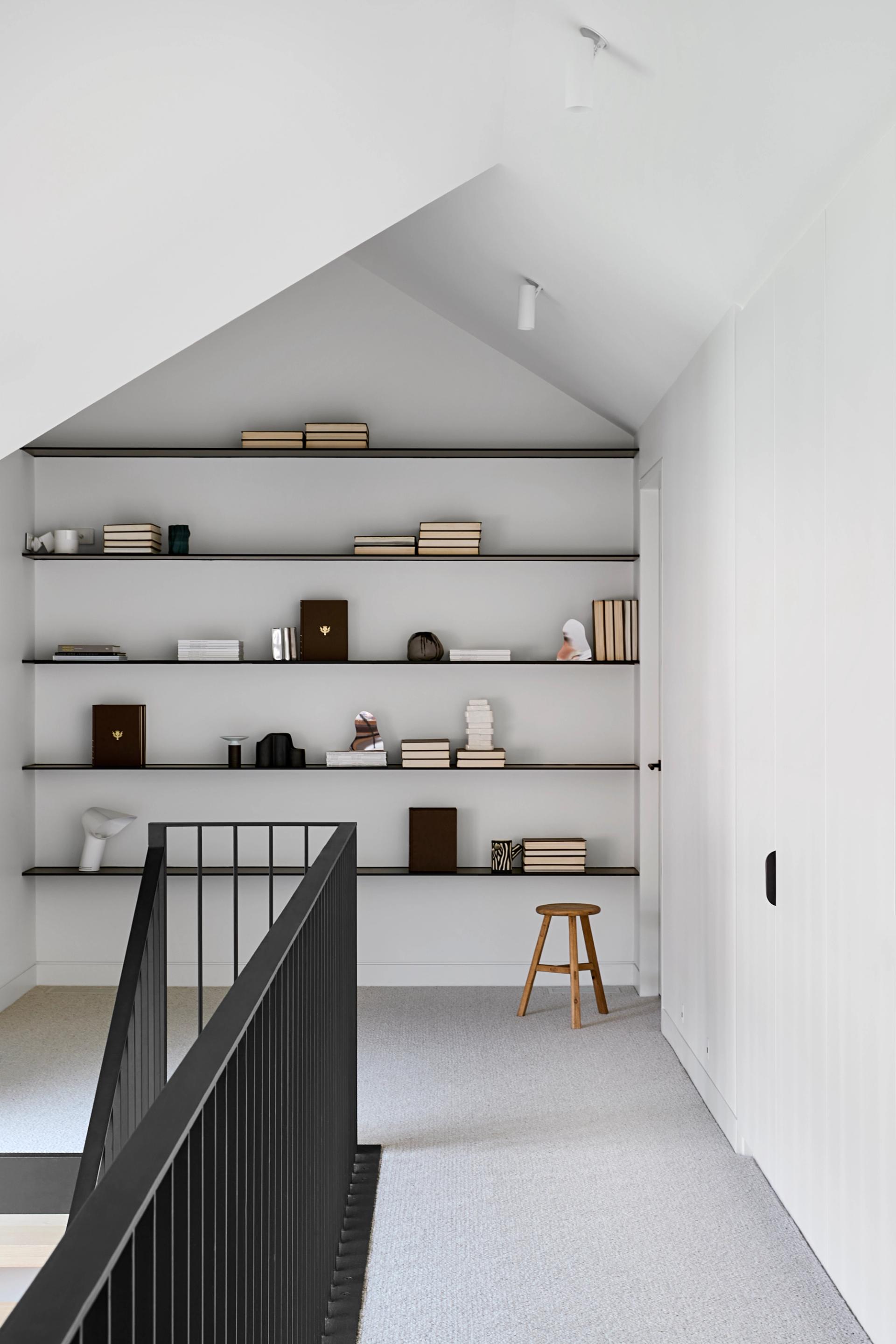 The upper level features a landing that doubles as a reading nook and modern display area.