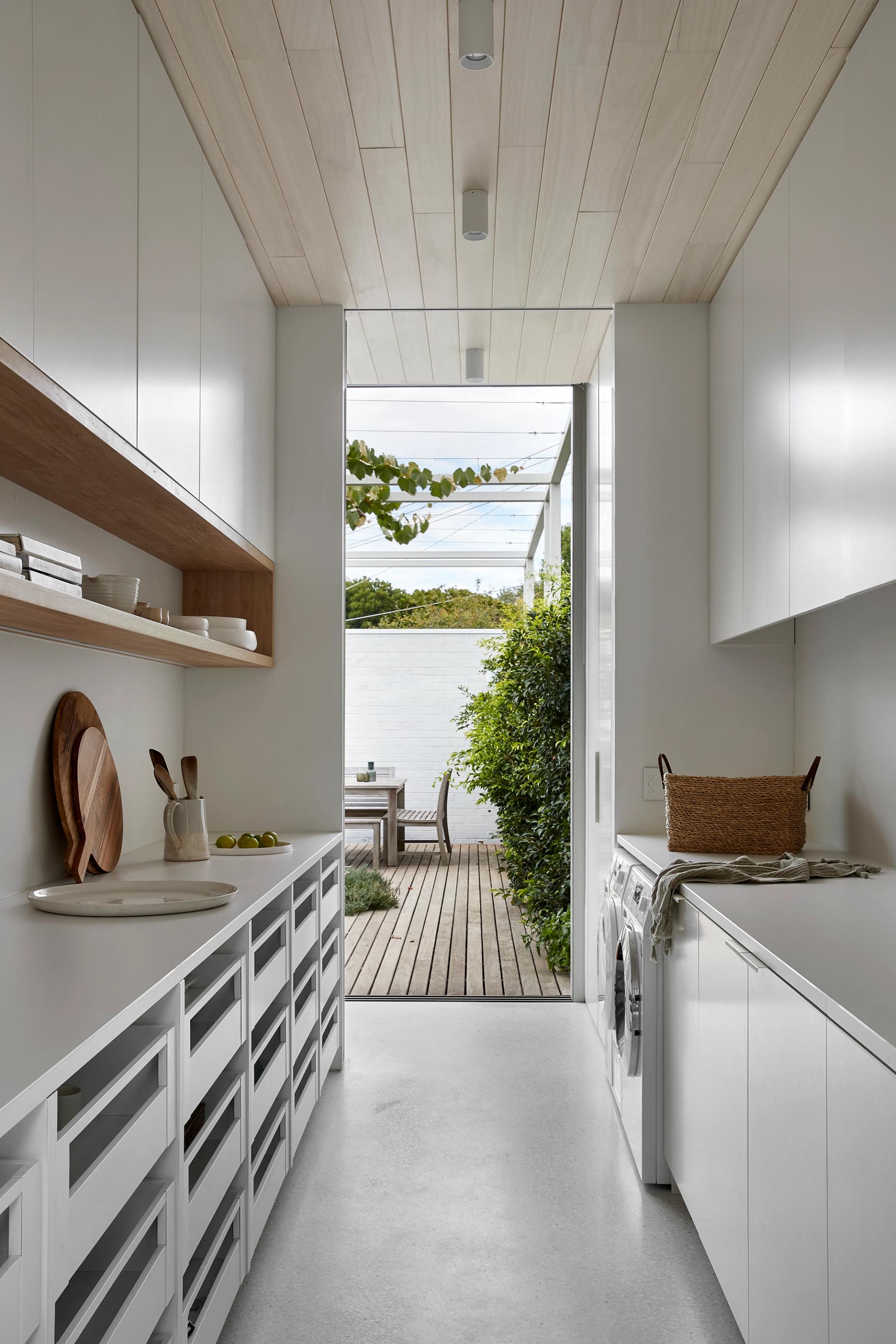 The kitchen galley serves as mudroom, pantry and laundry, with outlooks to the garden from both ends.