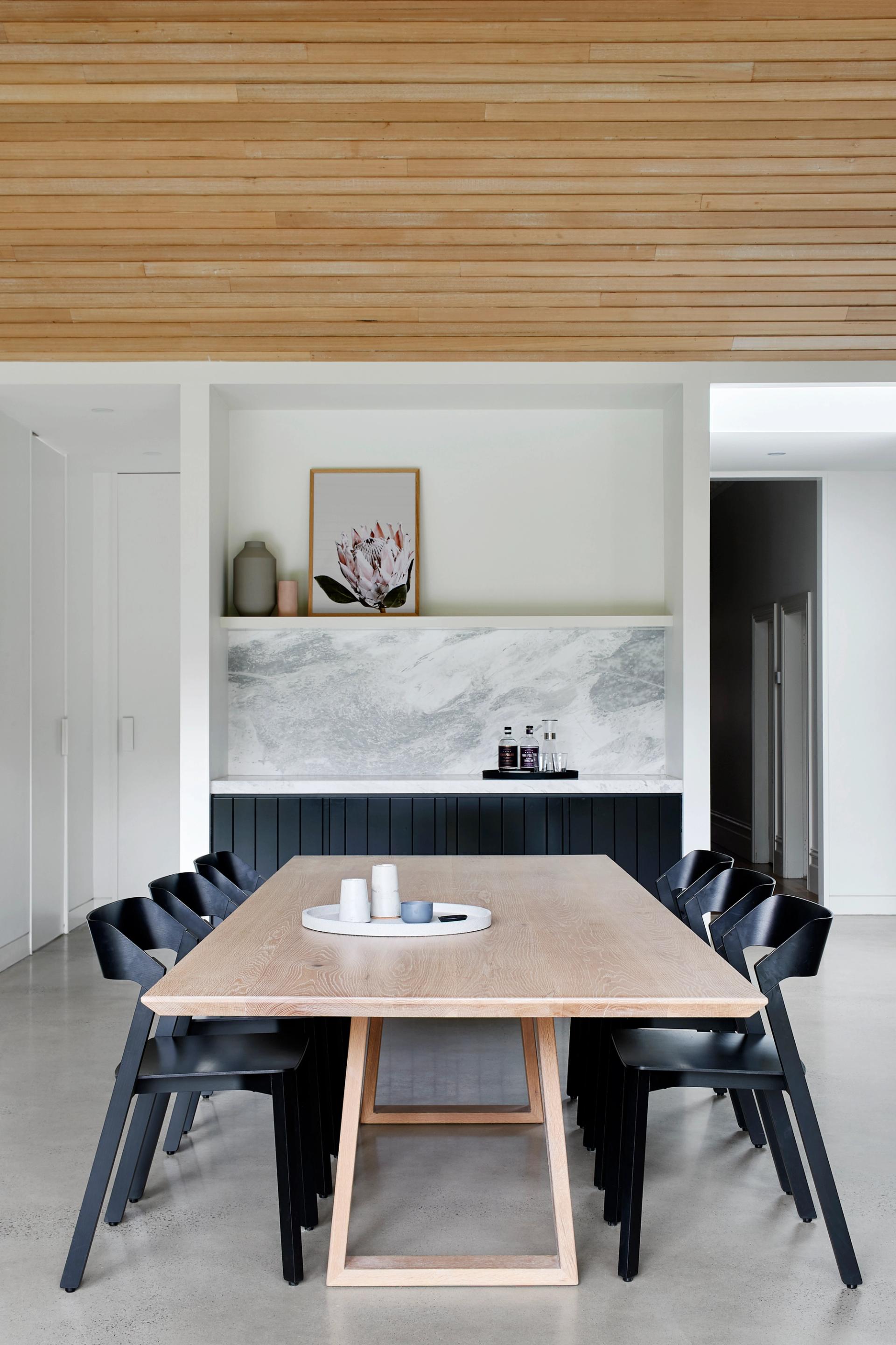The dining area's neutral palette of concrete, timber, stone and black cabinetry are a timeless backdrop for the growing family.