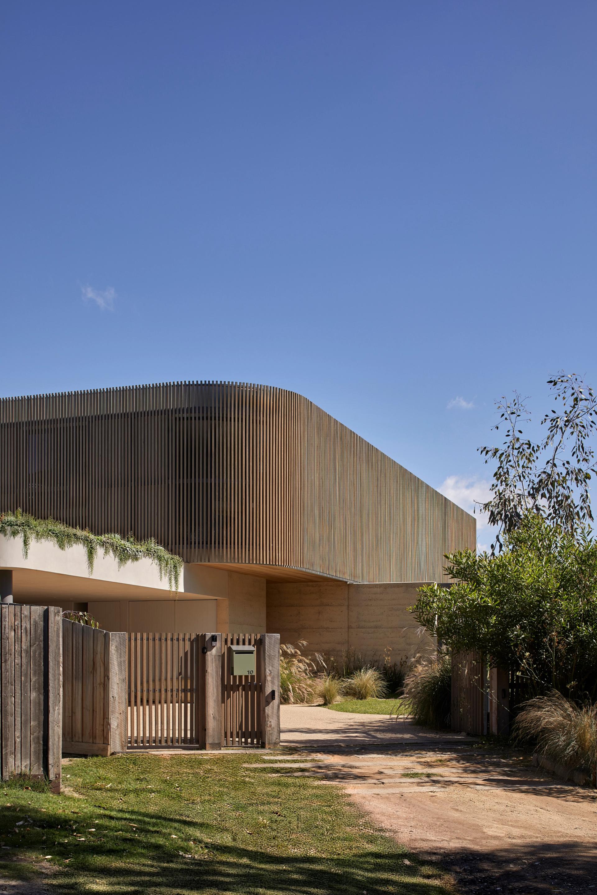 Barwon Dunes House by Eliza Blair Architecture featuring curved timber screening, rammed earth walls, coastal planting and sculpted dune-inspired forms in Barwon Heads.