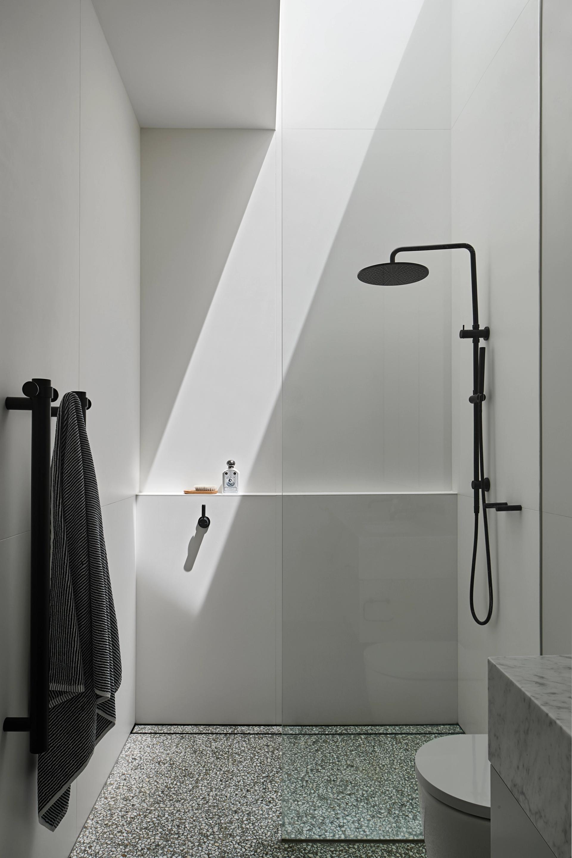 Bathrooms feature terrazzo flooring, large format white tiles and black tapware