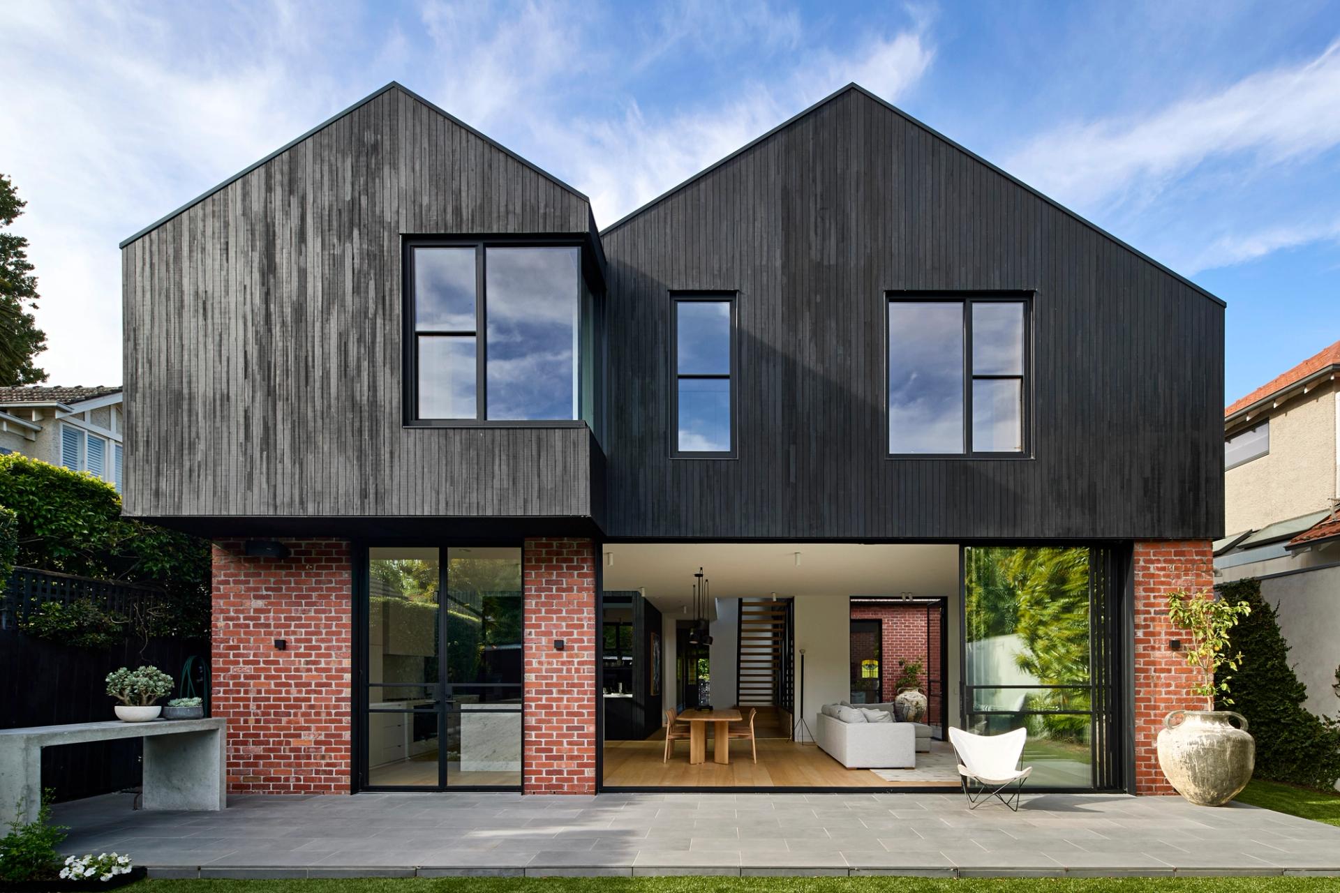 Recycled red brick walls are punctuated by black steel shrouds, while the upper volumes feature black stained thermally modified timber cladding.