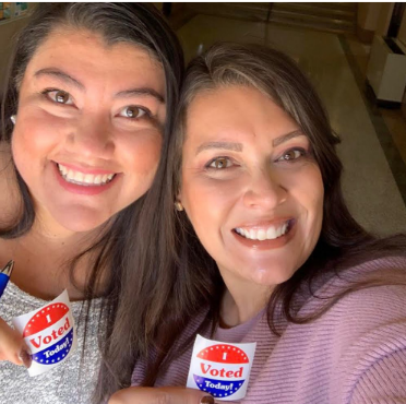 close up of two smiling Latinas with I voted stickers