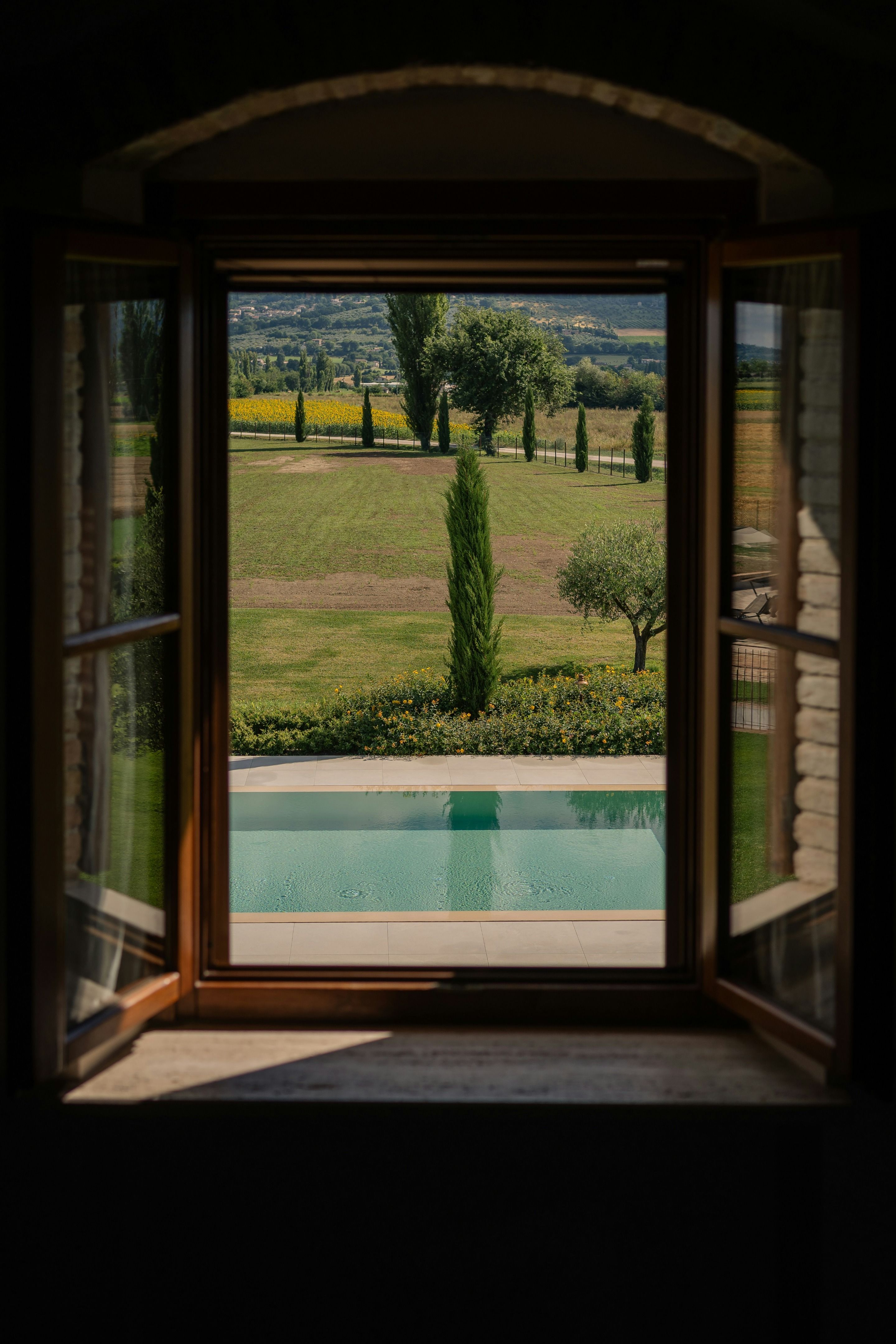 View from a living space onto a garden with a pool and the surrounding landscape.
