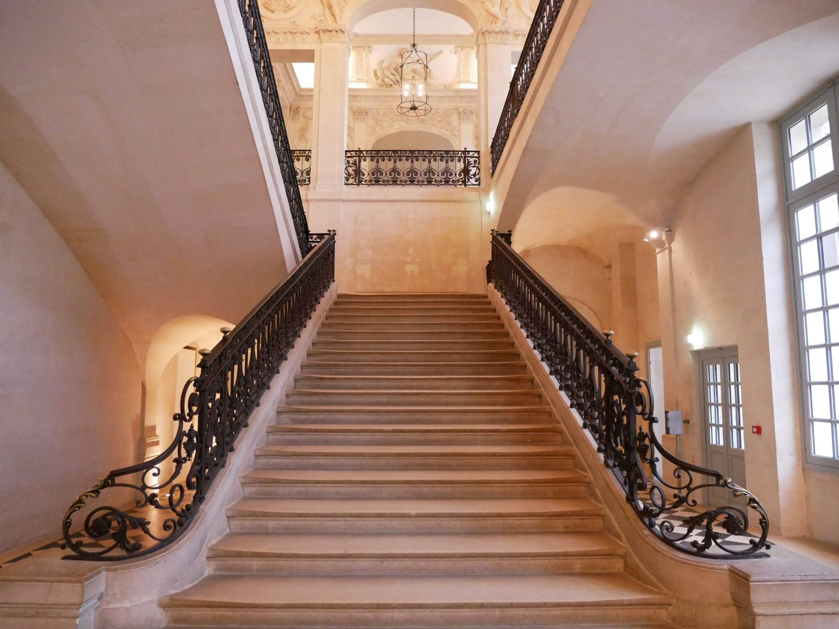 Historic staircase with stone steps and ornate railings inside an Italian building.