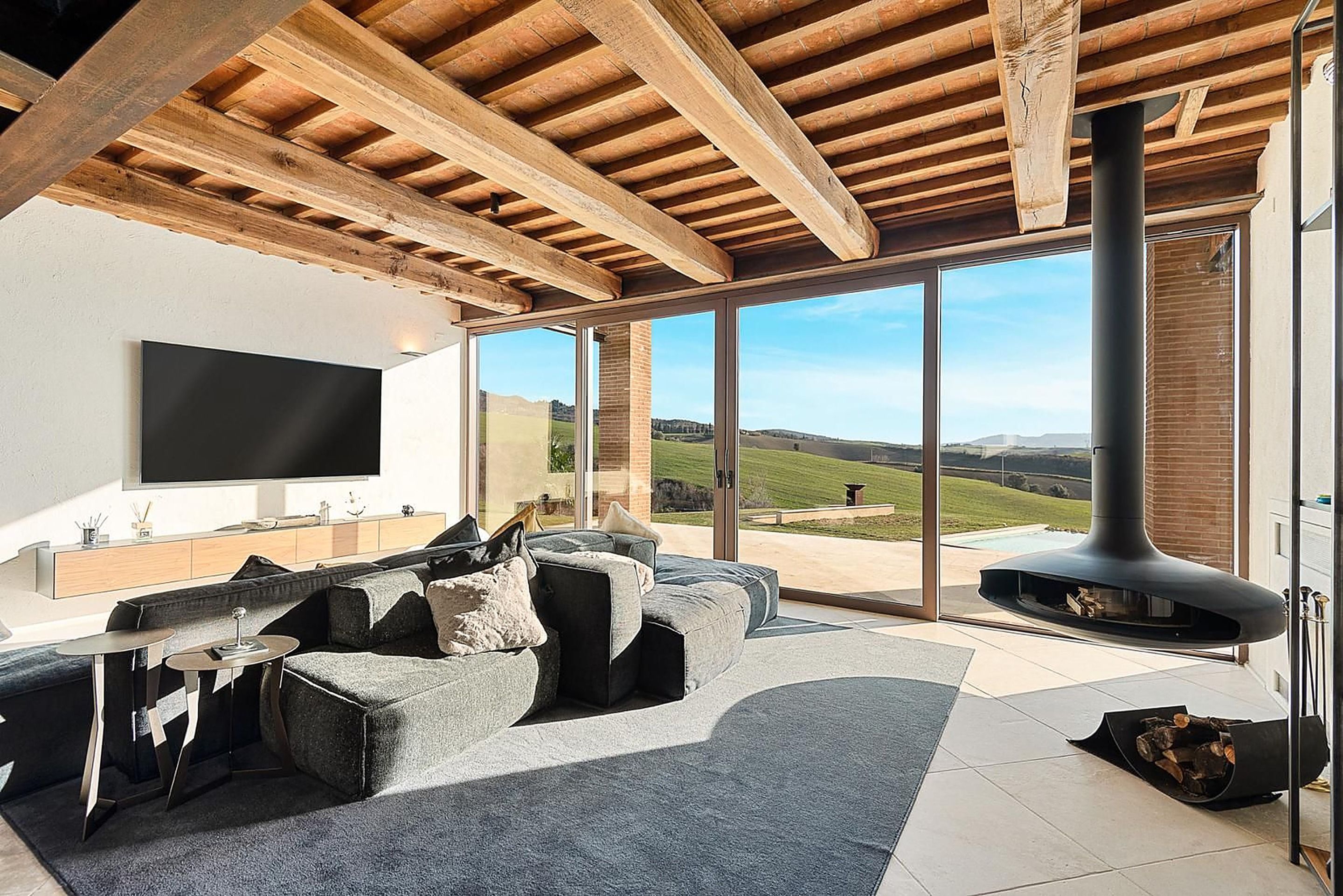 Bright living area with exposed timber beams, large windows and views of the surrounding countryside.