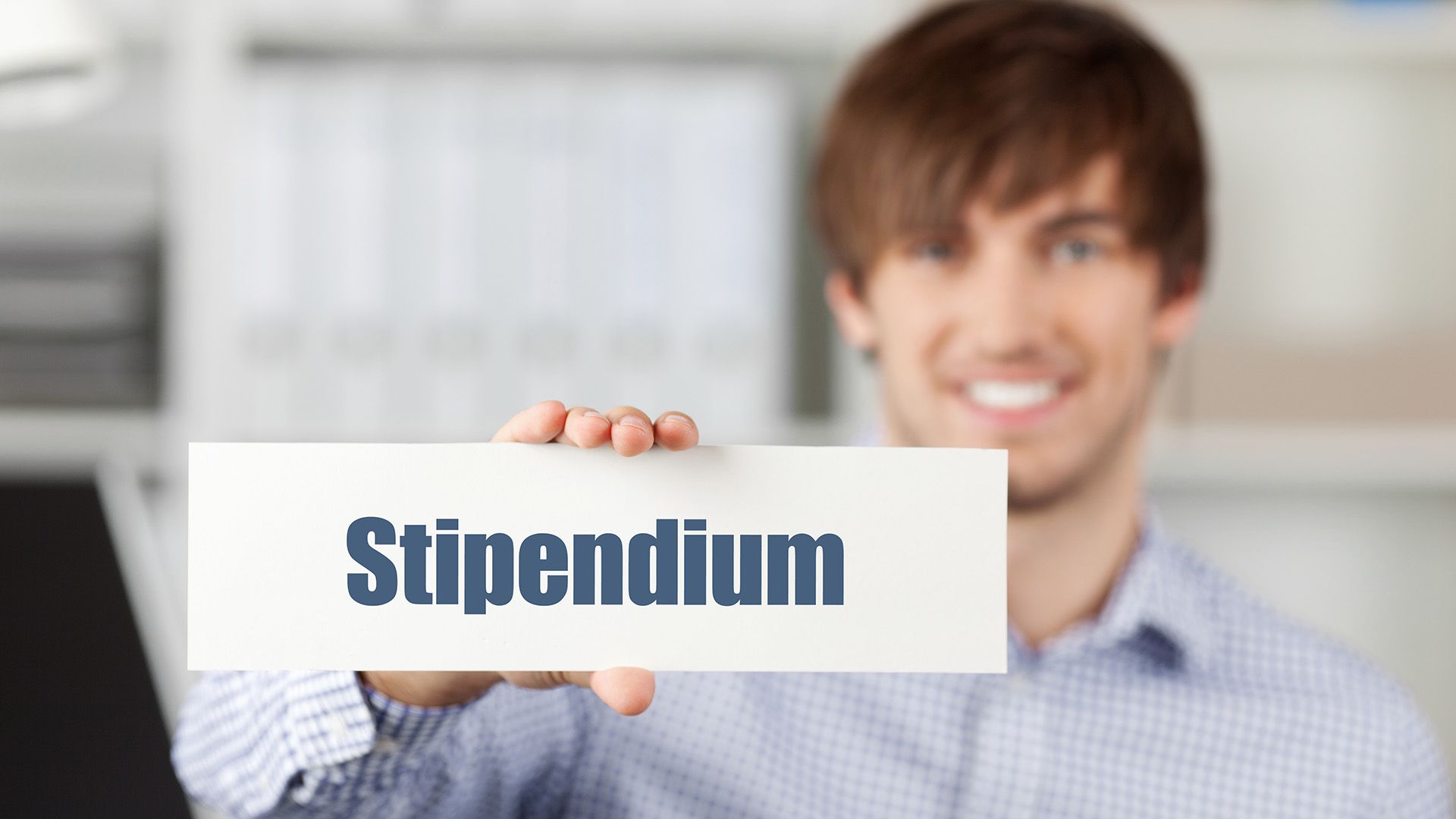 Mann hält Schild mit Aufschrift Stipendium.