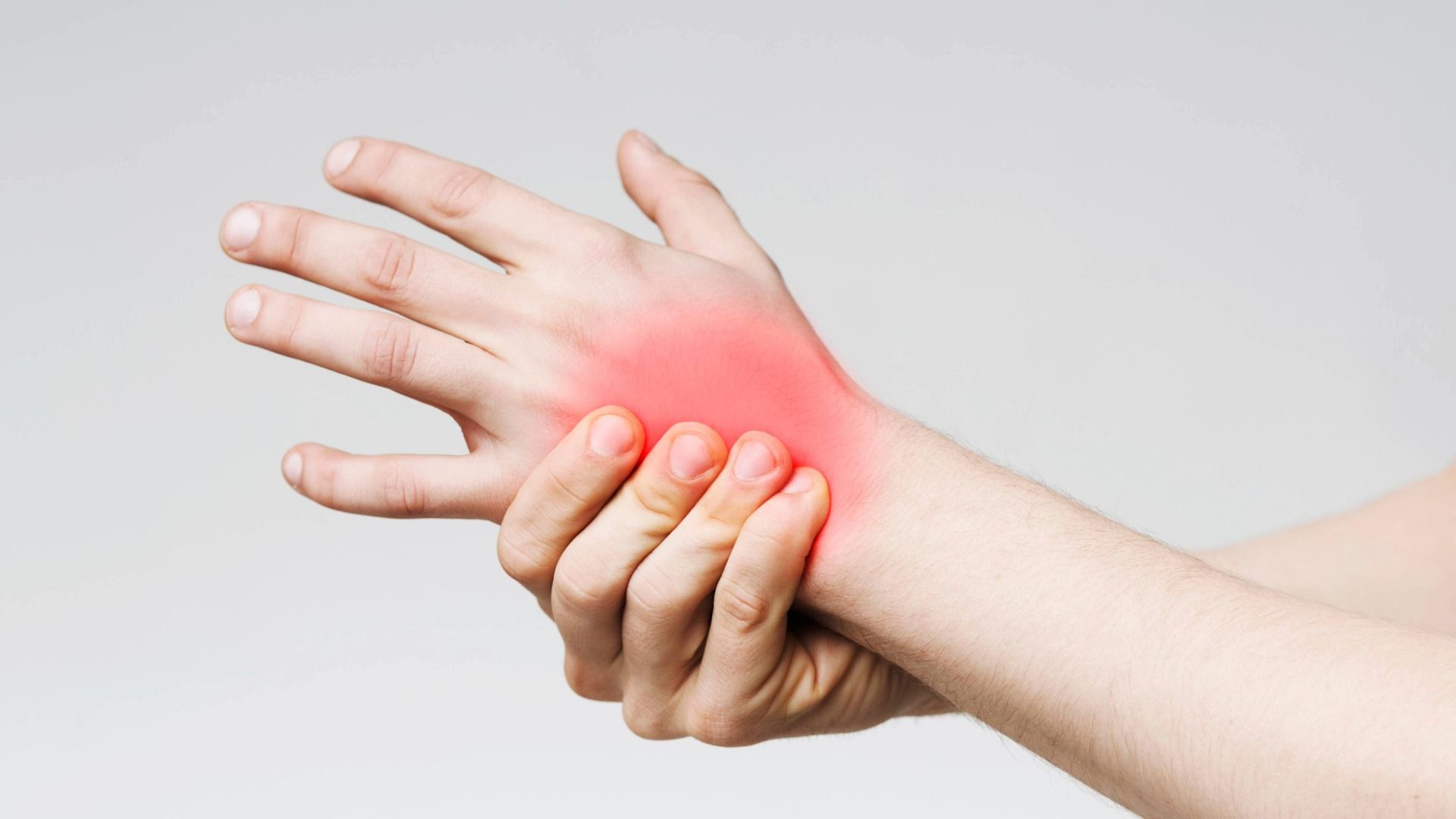 Hand umschließt schmerzendes Handgelenk. Roter Schmerzpunkt Handrücken.