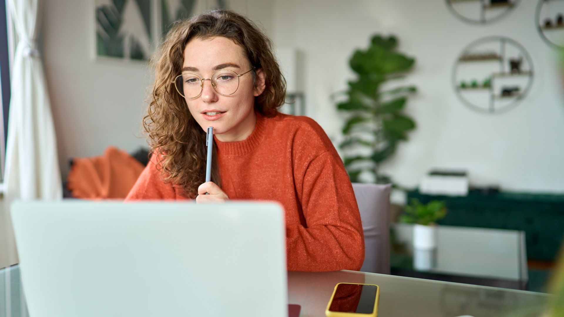 Studentin mit Kugelschreiber bei der Prüfungsvorbereitung lernt am Laptop.