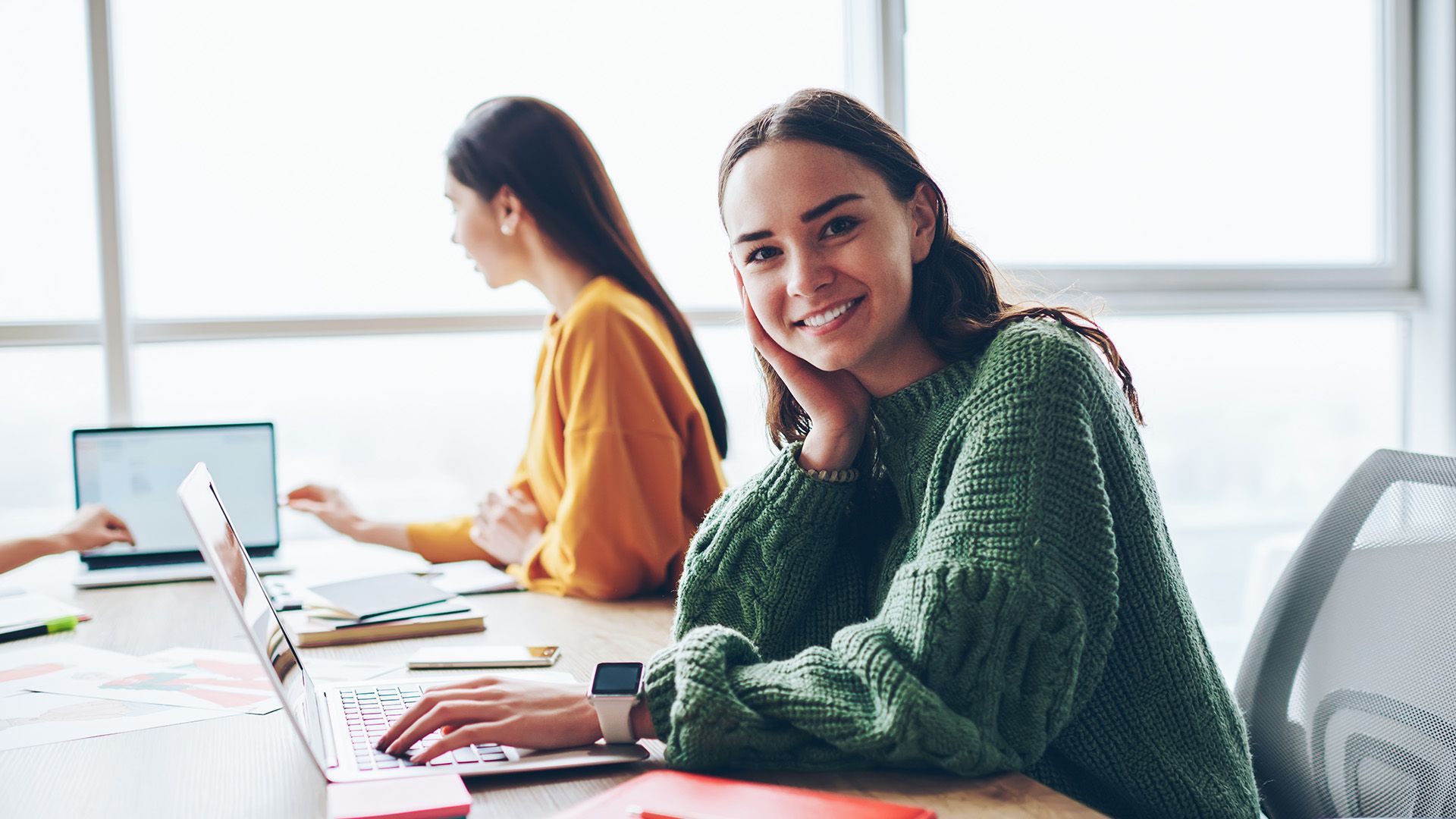 2 Studentinnen sitzen am Schreibtisch und lernen am Laptop.