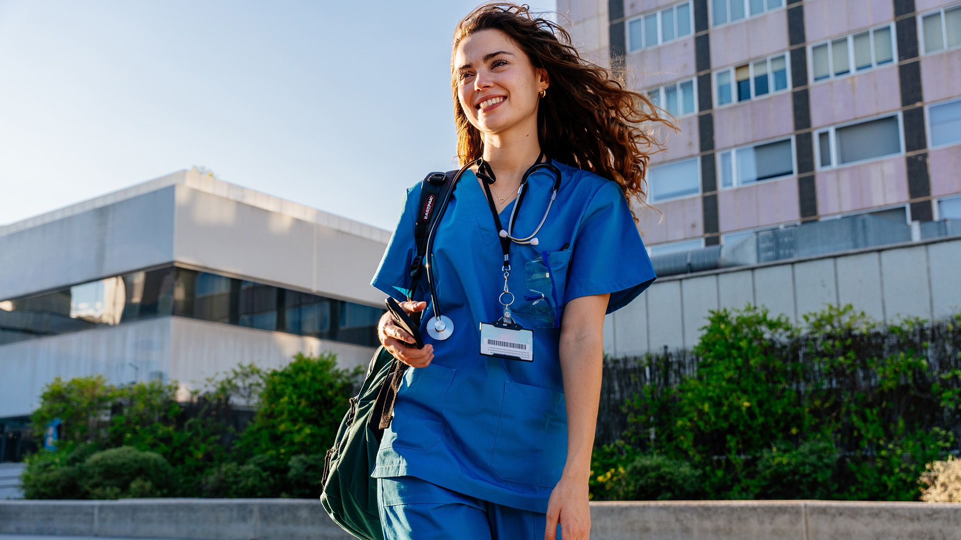 Junge Ärztin im blauen Kasak vorm Krankenhaus.