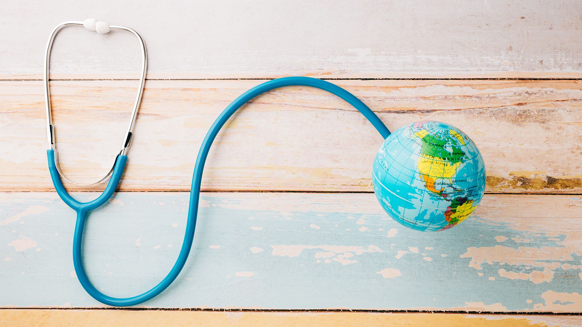 Blaues Stethoskop mit Weltkugel auf Holztisch.
