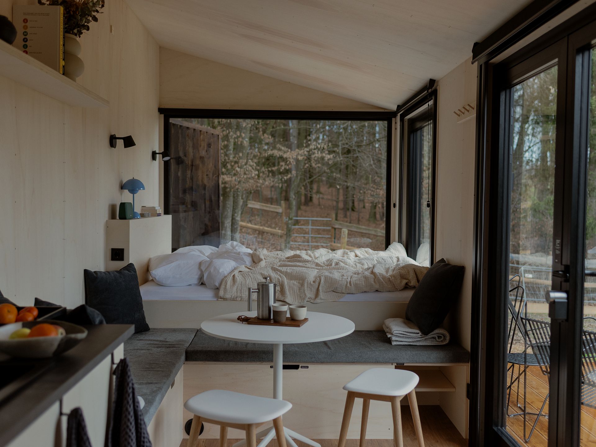 Blick durch die Cabin auf das Bett und durch das große Fenster hinaus in den Wald