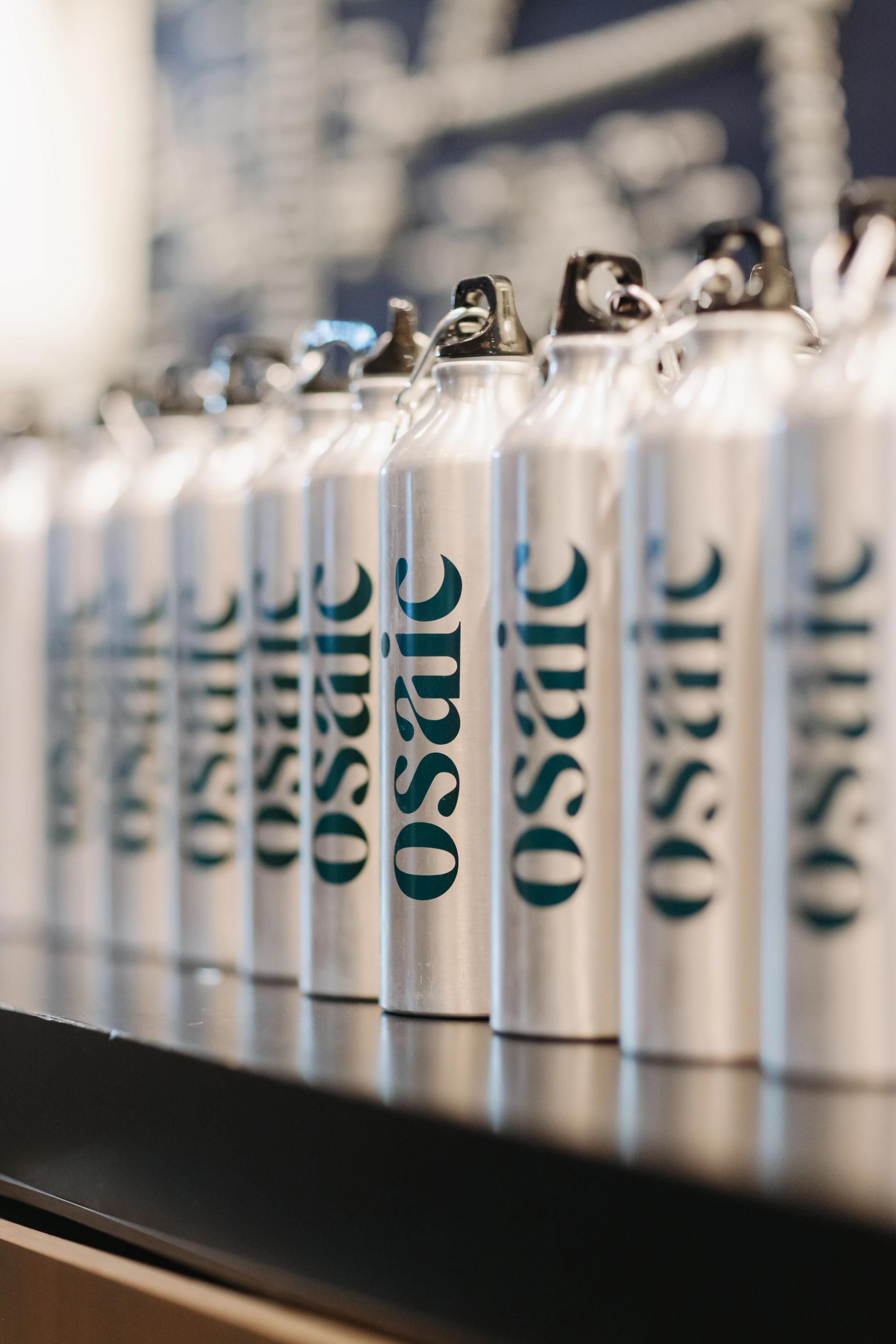 Water bottles neatly lined up and displaying the brand, Osaic