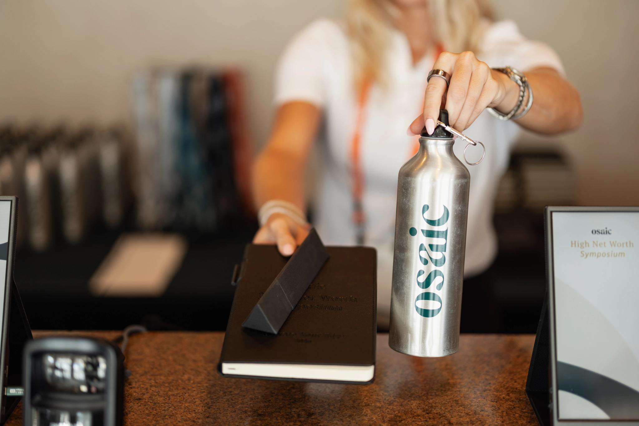 A woman passes Osaic items across a desk
