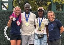 Four people, three of whom are wearing medals, pose and smile for a photo
