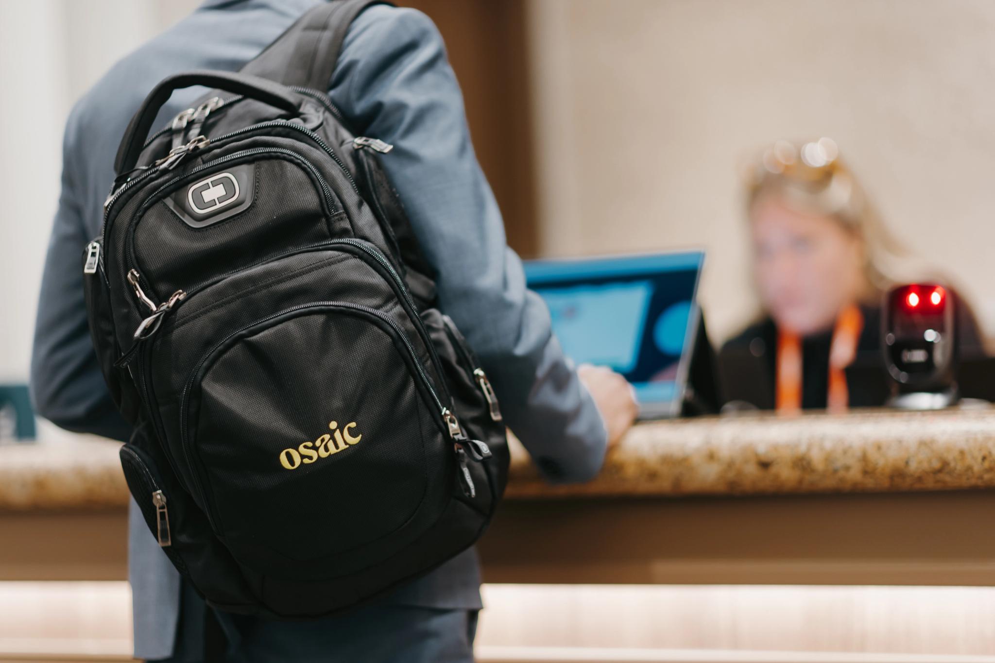 A Financial Professional carrying an Osaic branded backpack registers for the event