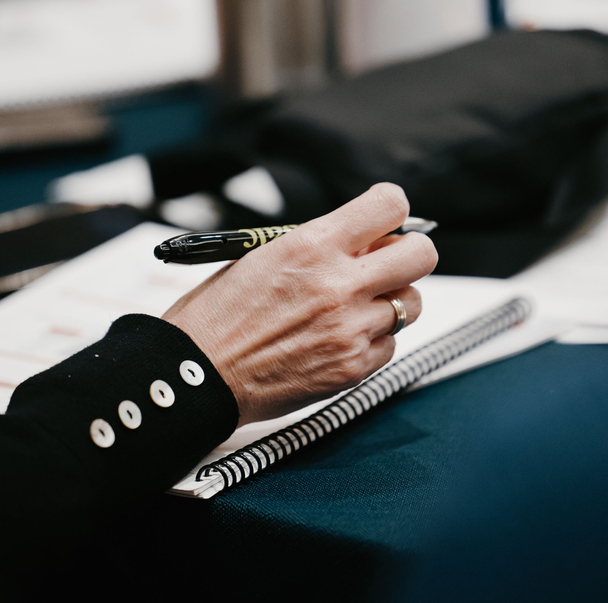 A woman holding an Osaic pen, poised to write in a notebook
