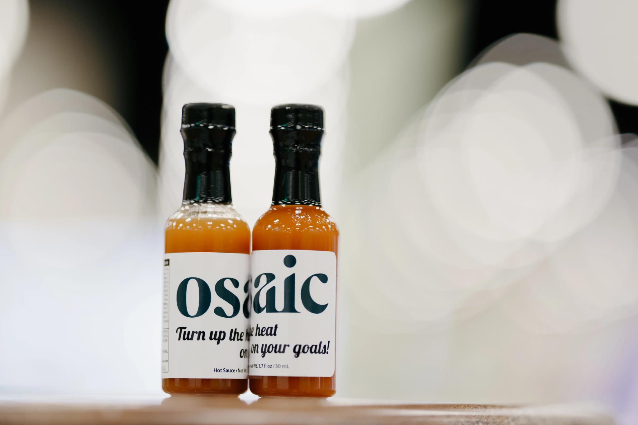 A pair of Osaic-branded bottles sitting together create one word