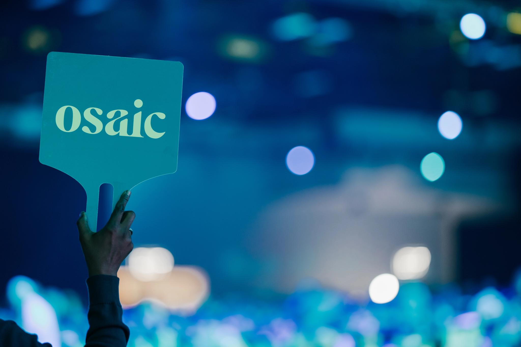 A Financial Professional holds up a sign, "Osaic"