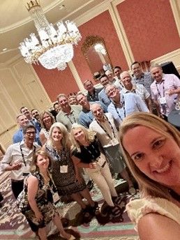 A group gathers under a chandelier for a photo