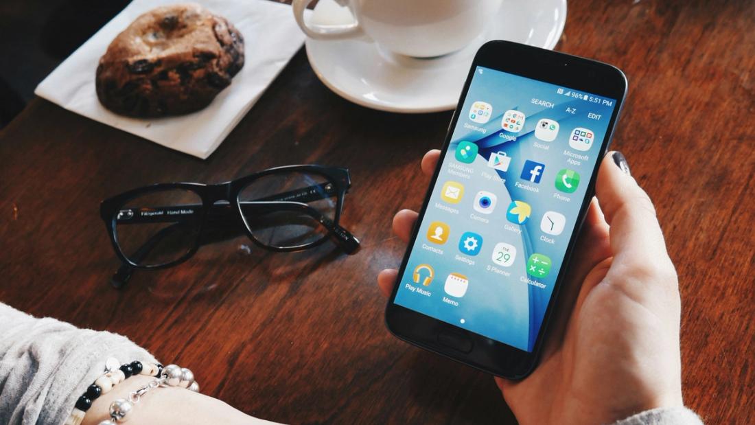 Uno smartphone in mano accanto a una tazza di caffè