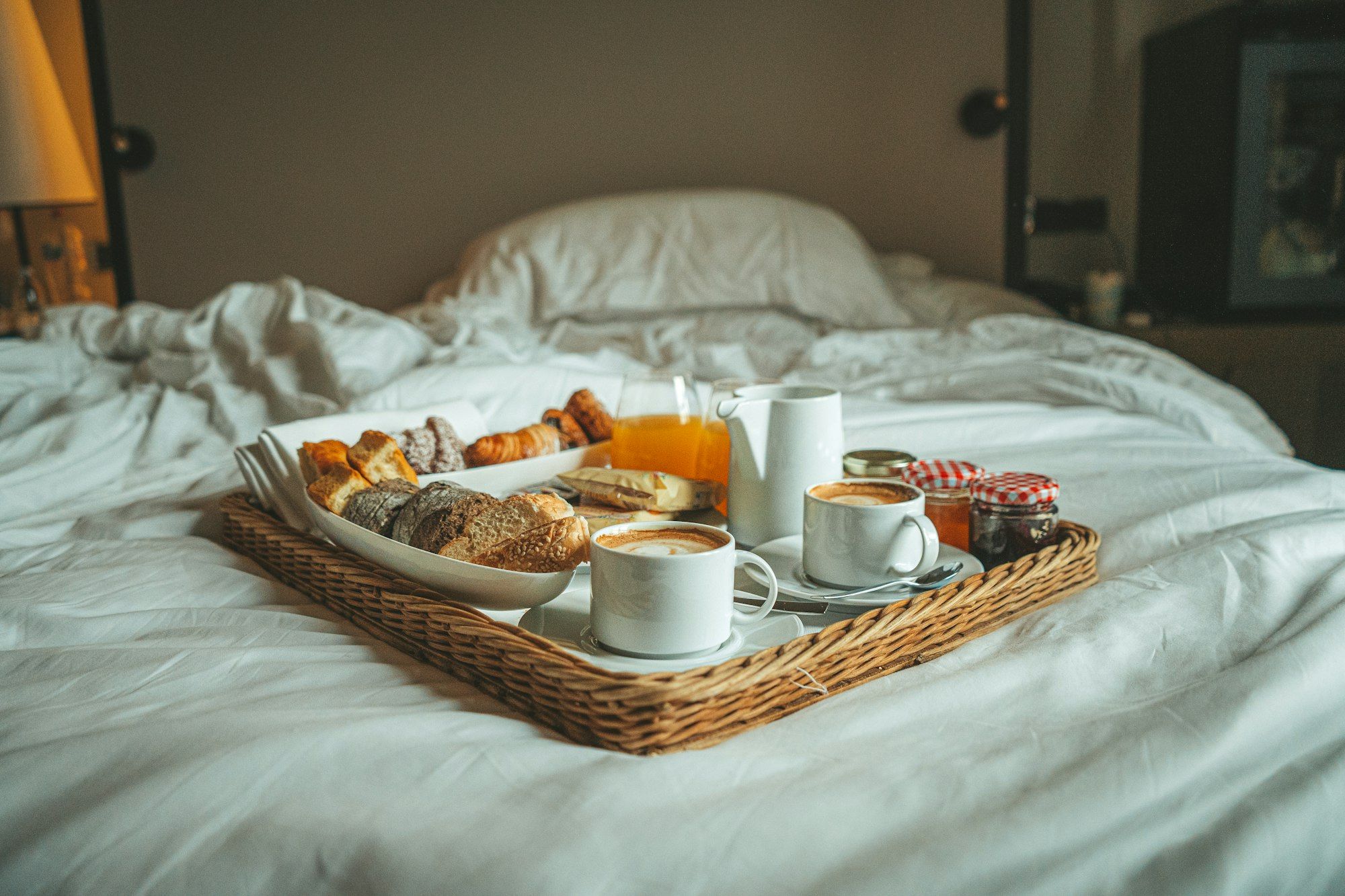 Vassoio della colazione su un letto con lenzuola bianche