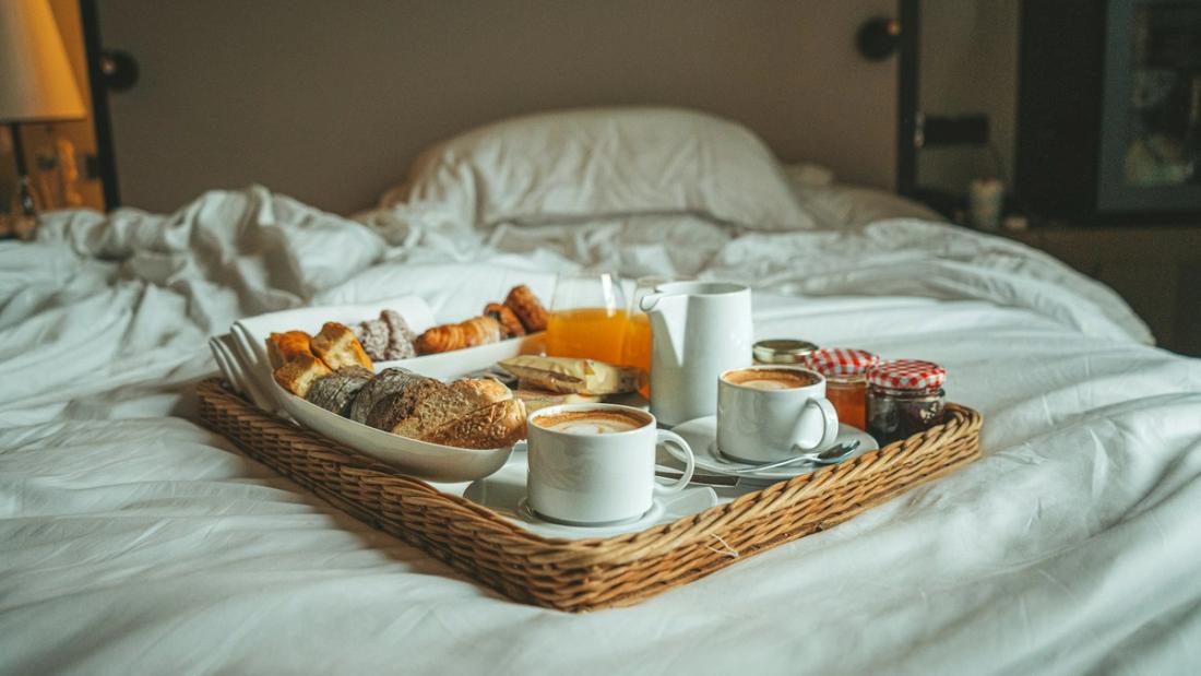 Vassoio della colazione su un letto con lenzuola bianche