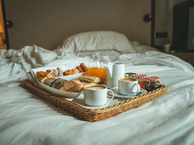 Vassoio della colazione su un letto con lenzuola bianche