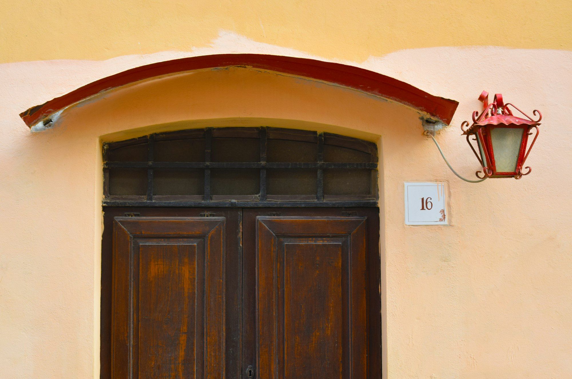 Portone in legno ad arco di una casa con applique accanto