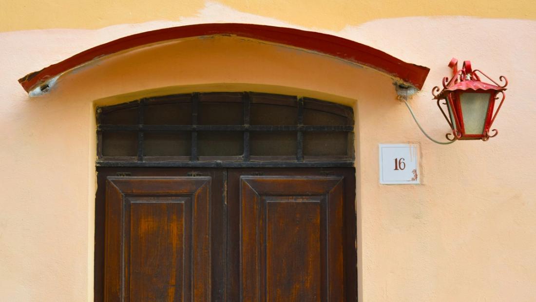 Portone in legno ad arco di una casa con applique accanto