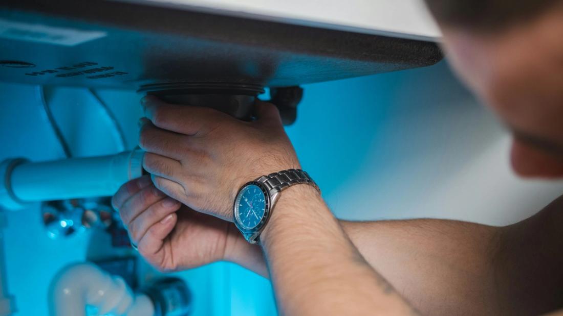 Un idraulico al lavoro sotto uno scaldabagno