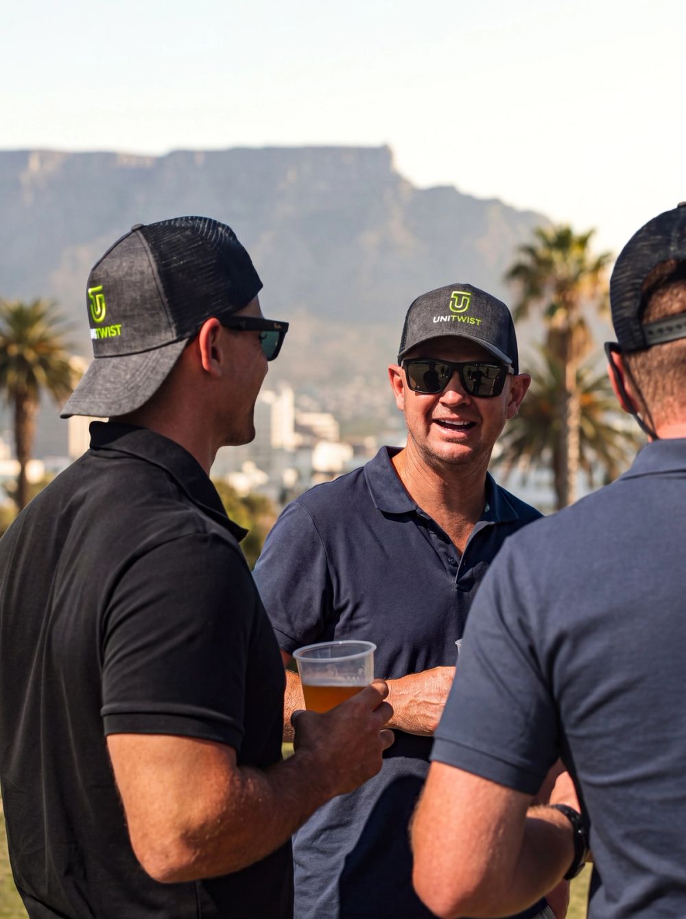 Unitwist team members wearing branded caps at an outdoor plumbing industry event in Cape Town.