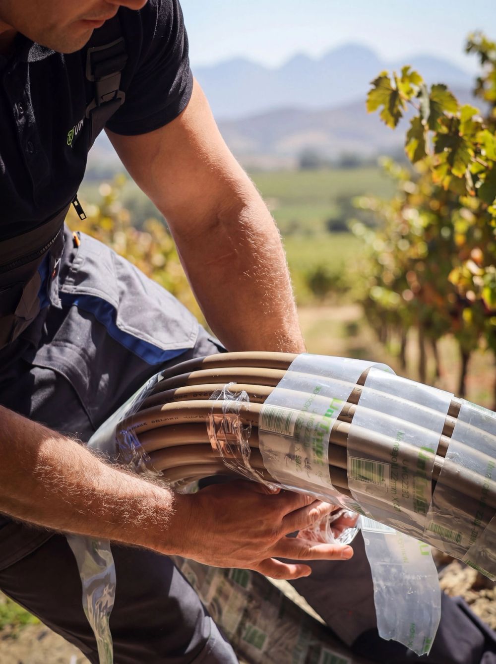 Unitwist installer handling a coil of Monogold PP-R pipe during an outdoor plumbing installation.