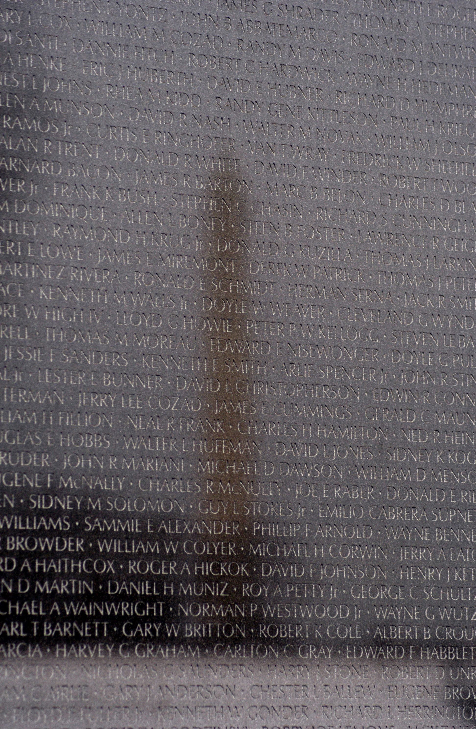 The Washington Monument reflected in the polished black granite wall of the Vietnam Veterans Memorial.