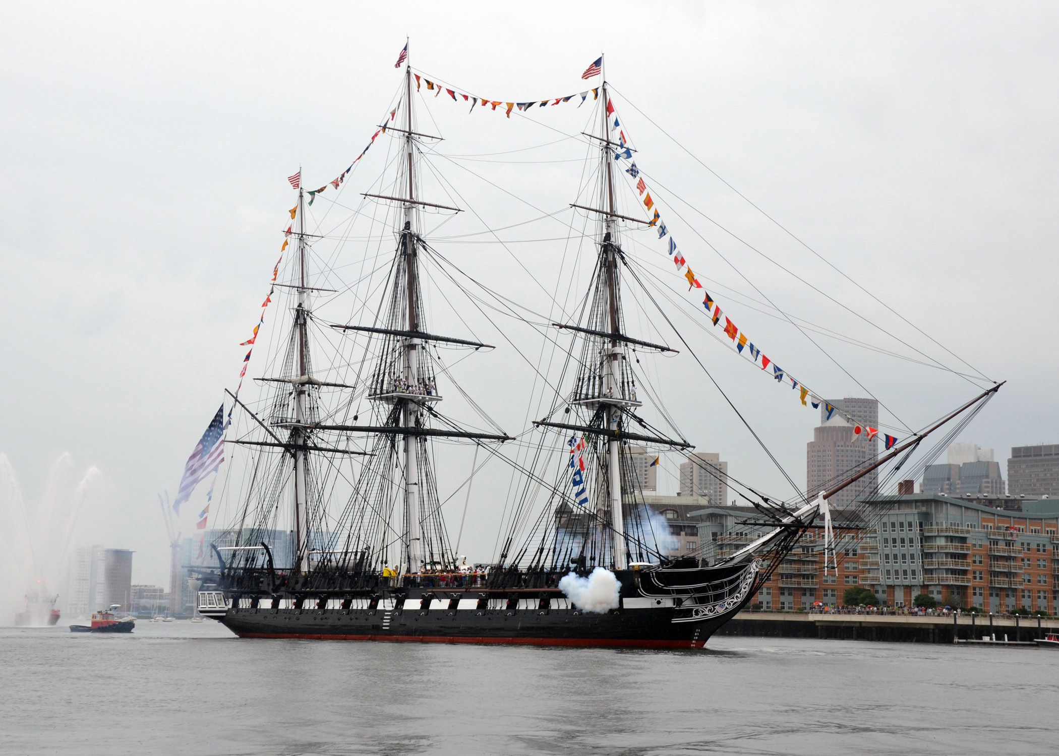 USS Constitution firing a cannon salute in Boston Harbor.