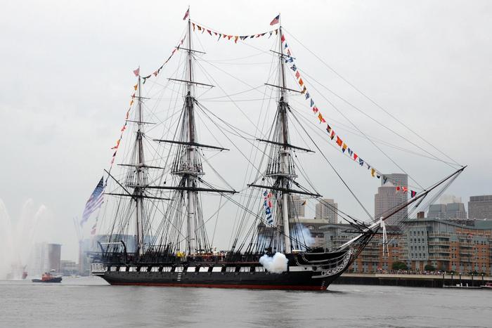 USS Constitution firing a cannon salute in Boston Harbor.