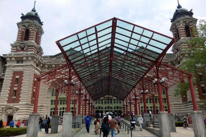 The main immigration building on Ellis Island, its red-brick towers and copper domes seen across the front lawn.