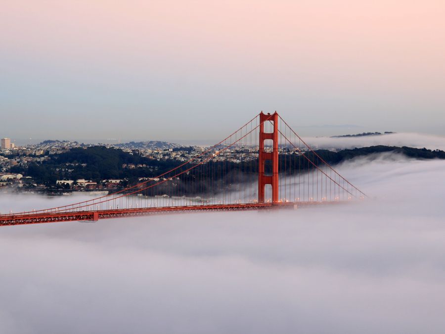 The Golden Gate Bridge at sunset, partly veiled in fog.