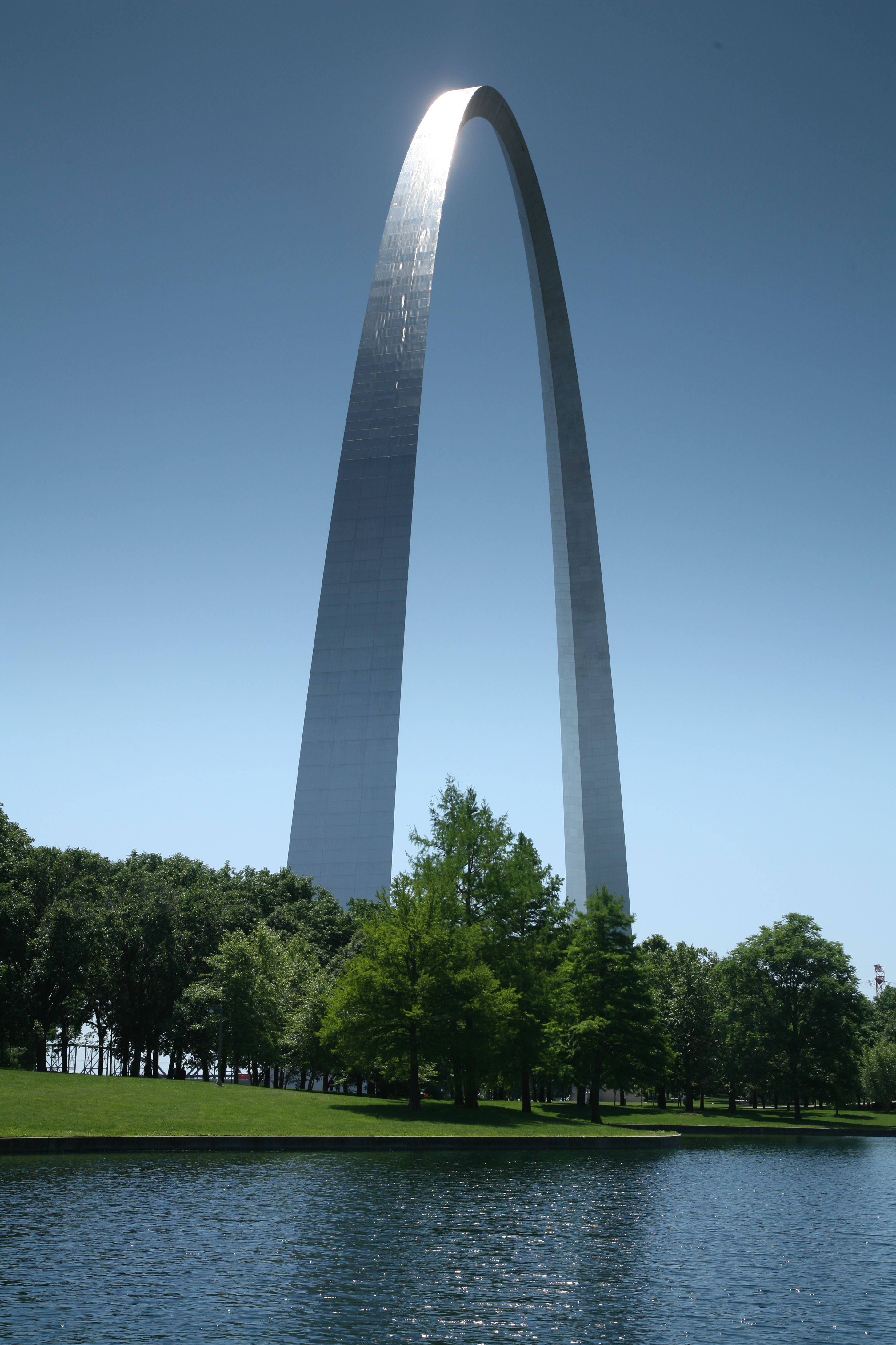 The stainless-steel Gateway Arch reflected in water.