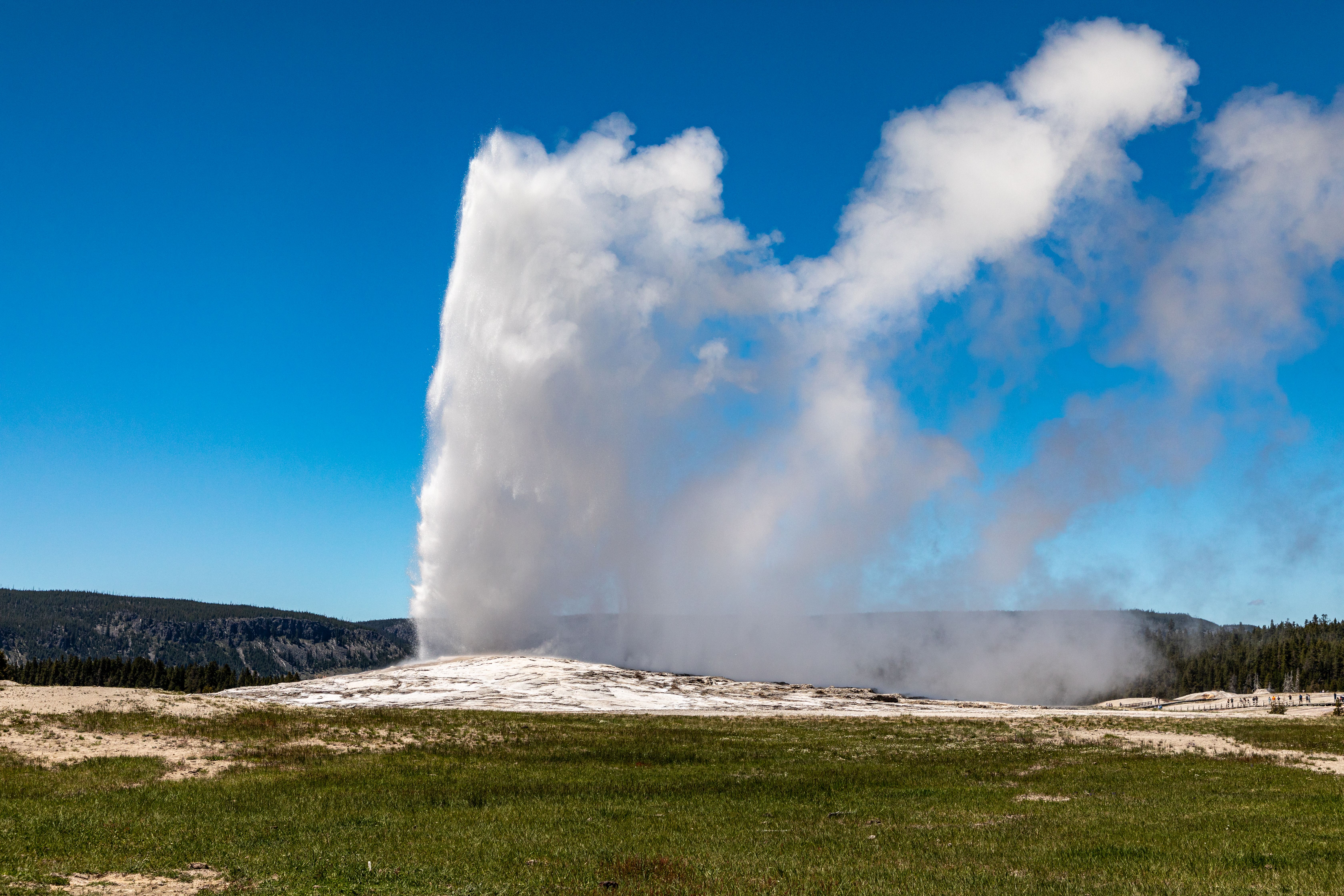 Visitors watching Old Faithful erupt from the surrounding boardwalk.