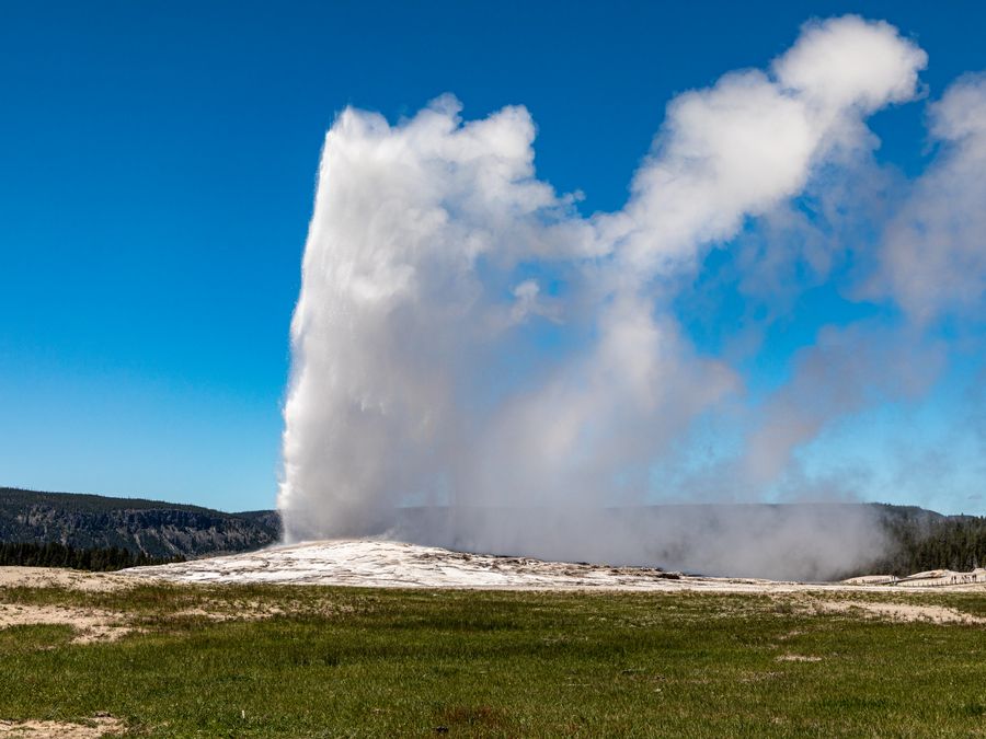 Visitors watching Old Faithful erupt from the surrounding boardwalk.