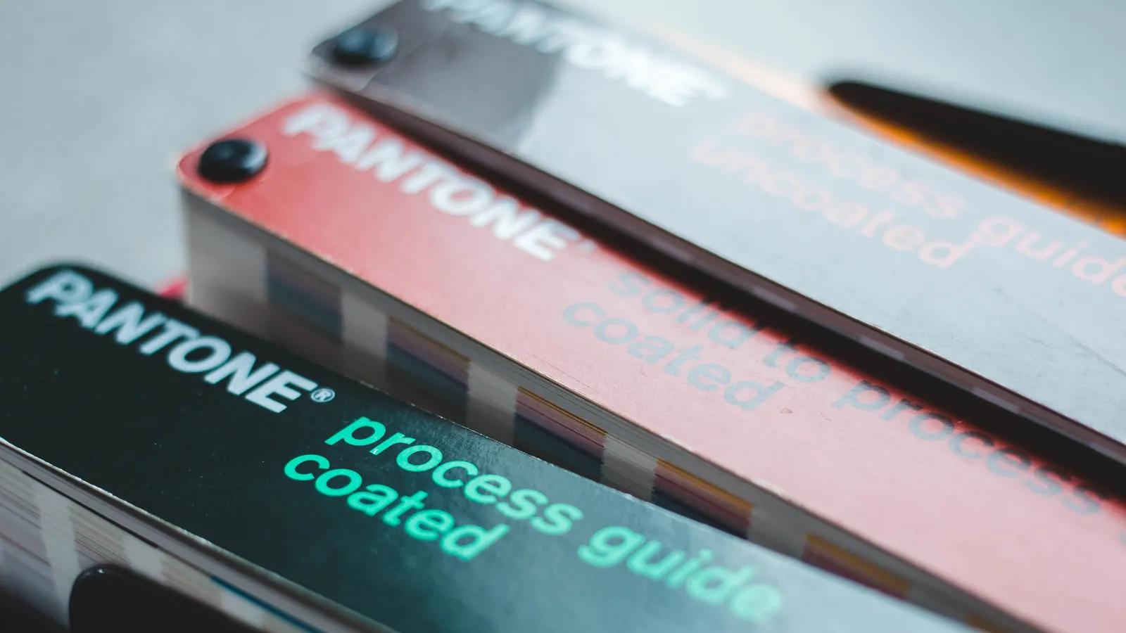 Printed colour swatch books fanned open on a table, the reference used to check brand values against real stock.